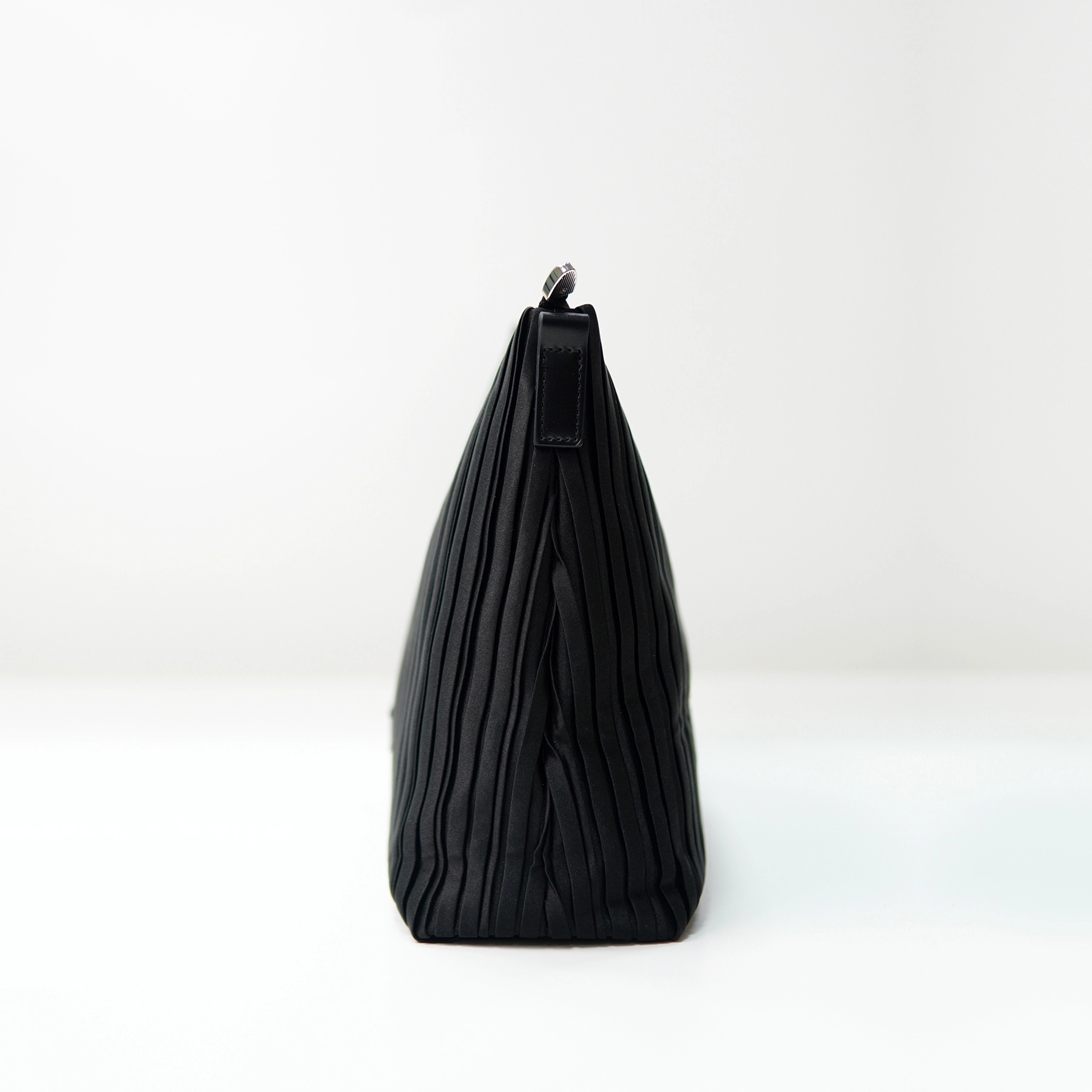 Side profile of pleated black handbag sample for custom handbag manufacturing review