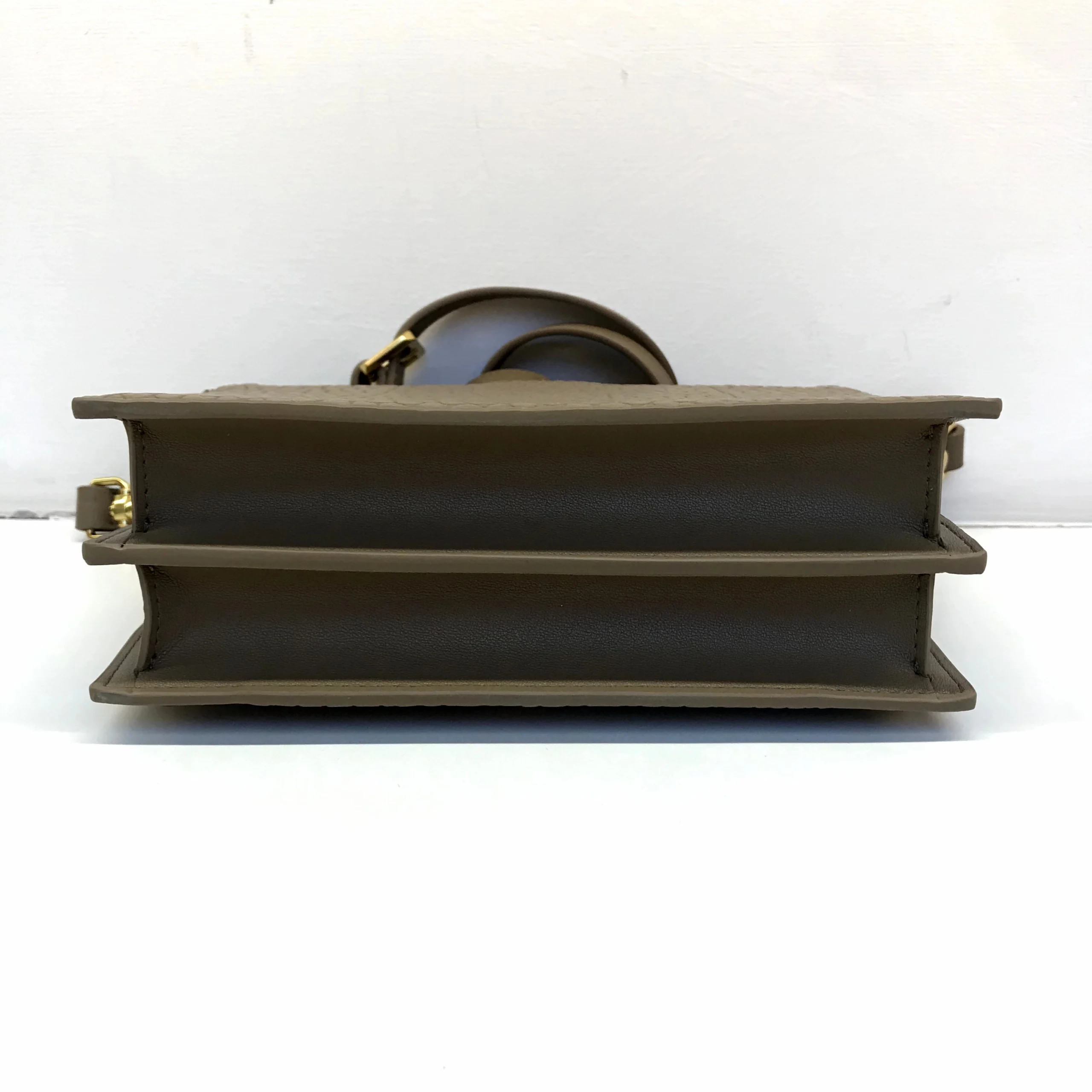 Side profile handbag sample documenting custom handbag manufacturing structure and hardware placement